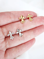 silver and gold fleur de lis earrings in hand