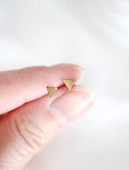 tiny gold triangle studs in hand