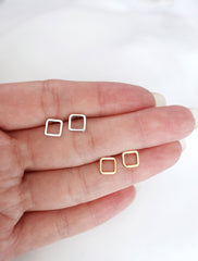 gold and silver open square stud earrings in hand
