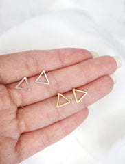 silver and gold open triangle studs in hand