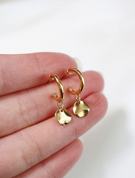 gold hoop earring with hammered disc charm in hand