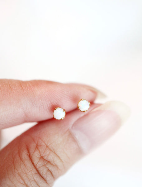 tiny opal gemstone studs held in hand