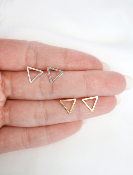 silver and gold open triangle studs in hand