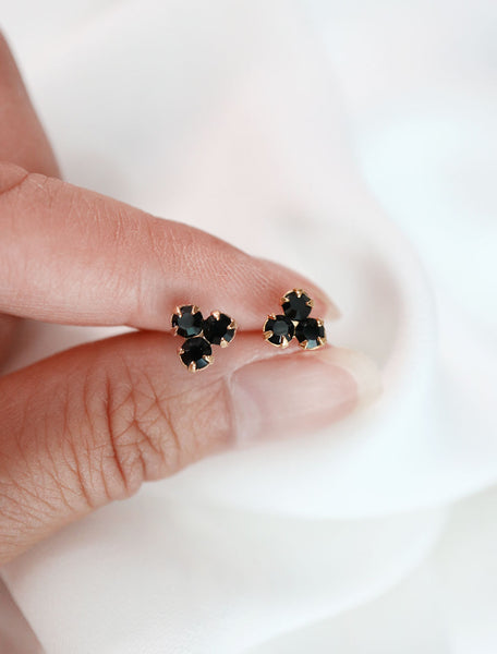 gold filled trefoil stud earrings with black crystals in hand