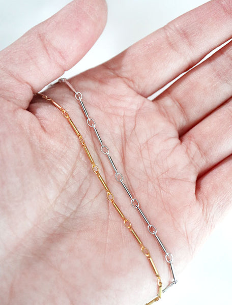 gold and silver bar chain necklaces in hand