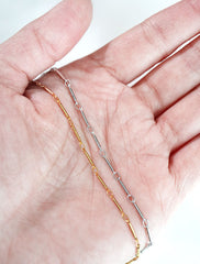 gold and silver bar chain necklaces in hand