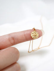 tiny horoscope necklace in hand
