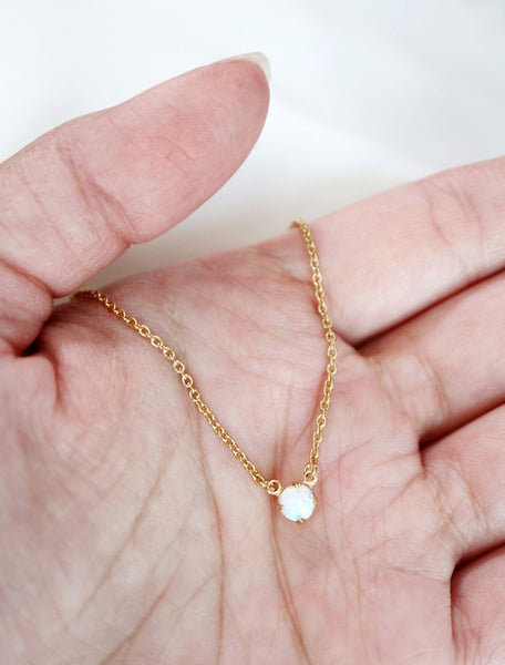 tiny opal pendant necklace in hand
