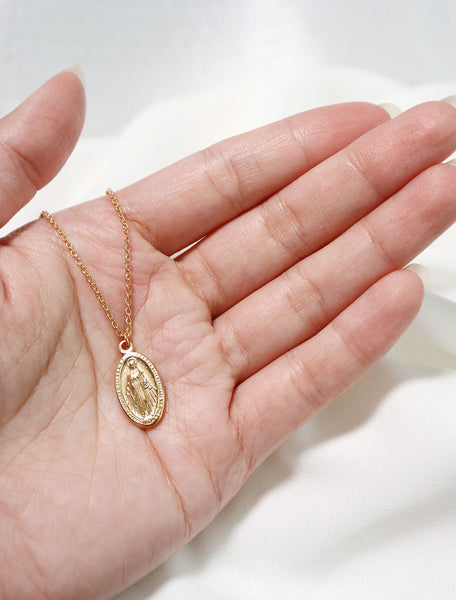virgin mary necklace in hand